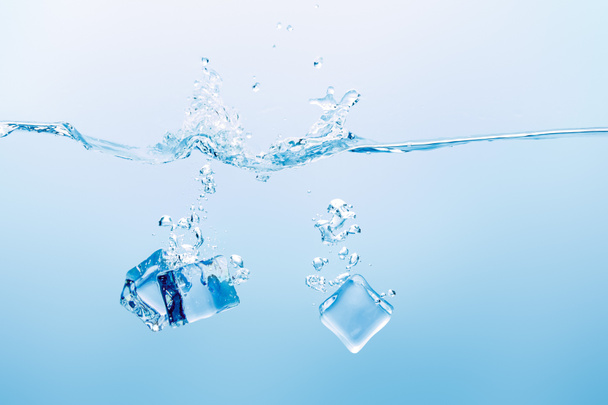 прозрачная чистая вода с брызгами и кубиками льда на синем фоне
 - Фото, изображение
