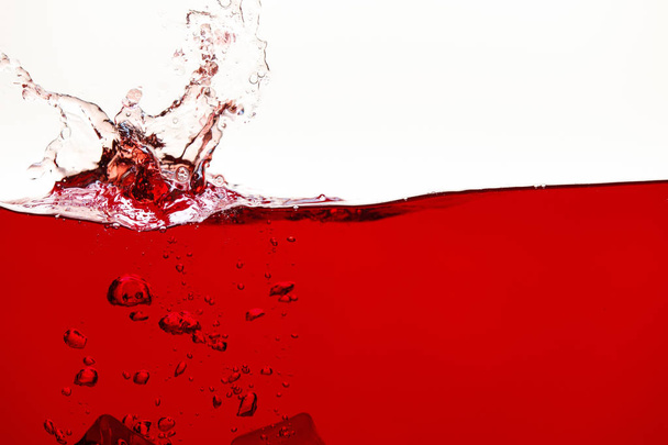 rode heldere vloeistof met Splash en bubbels geïsoleerd op wit - Foto, afbeelding
