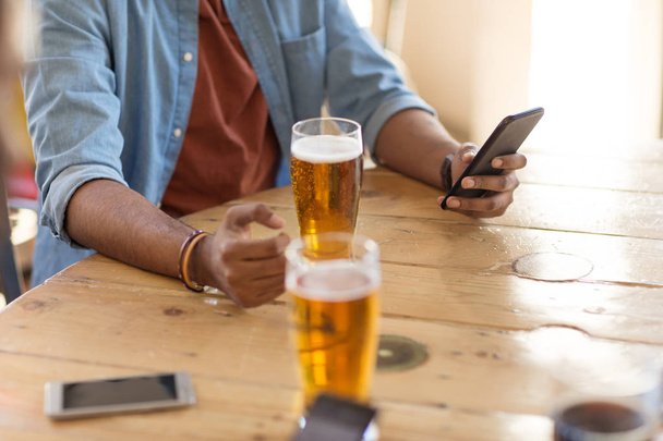 man with smartphone drinking beer at bar or pub - Фото, изображение