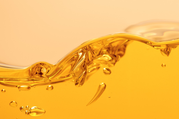 líquido brilhante amarelo ondulado com respingo e bolhas isoladas no amarelo
 - Foto, Imagem