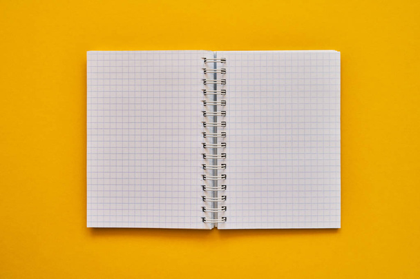 Vista superior de cuaderno abierto con páginas en blanco. cuaderno escolar sobre fondo amarillo, bloc de notas en espiral
 - Foto, Imagen