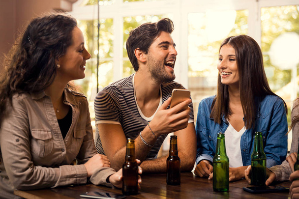 Eine Gruppe von Freunden an der Bar trinkt ein Bier  - Foto, Bild