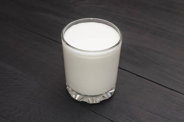 A glass with kefir, yogurt, milk on a black wooden background. - Fotoğraf, Görsel