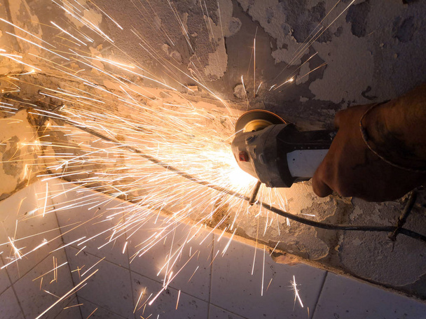 Trabalhador da Construção a cortar ferro da parede. com moedor. Faíscas enquanto moagem iron.Close-up
. - Foto, Imagem