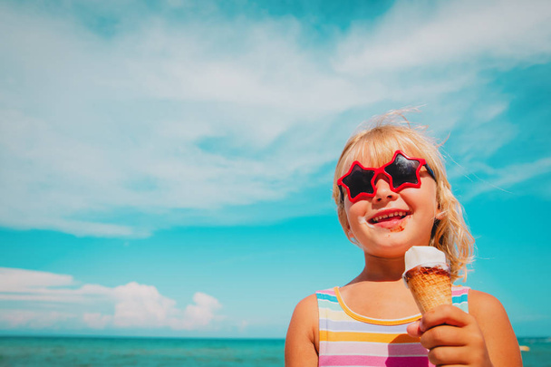 ビーチでアイスクリームを食べる幸せなかわいい女の子 - 写真・画像