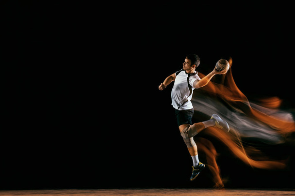 Young handball player against dark studio background in mixed light - Foto, afbeelding