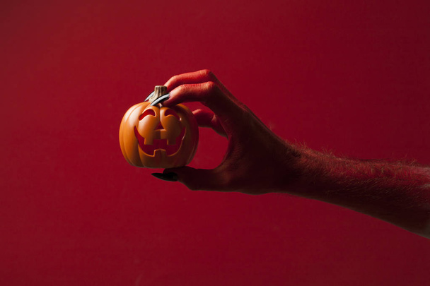 Red monster devil hand holing a pumpkin - Foto, Imagen