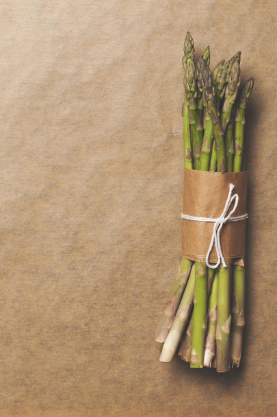 Asparagus tied in a bunch on a rustic brown paper background - Фото, изображение