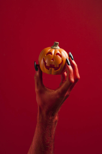 Red monster devil hand holing a pumpkin - Фото, зображення