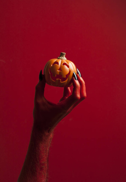 Red monster devil hand holing a pumpkin - Foto, afbeelding