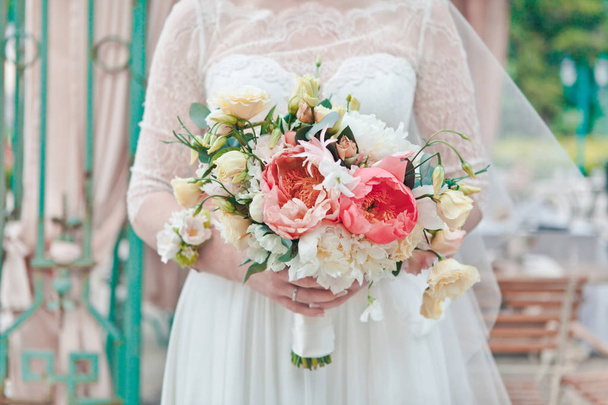 La mariée tient un bouquet de fleurs fraîches de printemps et d'été dans des couleurs pastel sur un fond flou, mise au point sélective
 - Photo, image