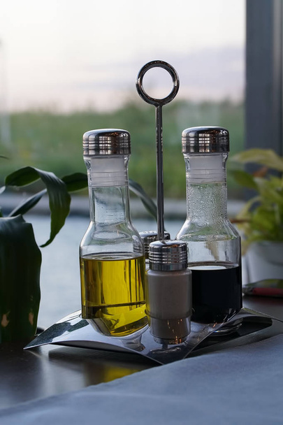 Bright yellow olive oil and black balsamic vinegar whis pepper and solt on the restaurant. - Foto, afbeelding