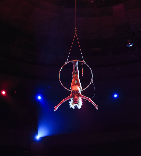 Aerial acrobat in the ring. A young girl performs the acrobatic elements in the air ring - Fotoğraf, Görsel
