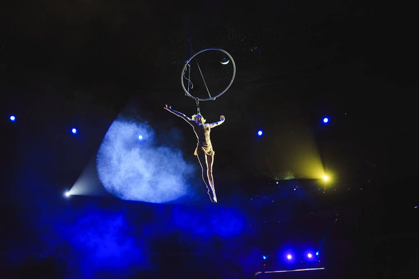 Aerial acrobat in the ring. A young girl performs the acrobatic elements in the air ring - Foto, Bild