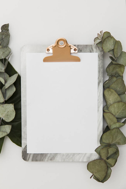 Clipboard with blank paper mockup with eucalyptus leaves, top vi - Photo, Image