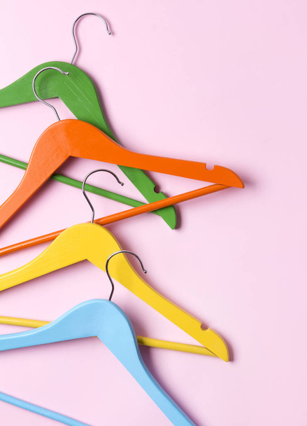 Creative flat lay multicolor wooden hangers at pink pastel background with copy space minimalist style. - Fotó, kép