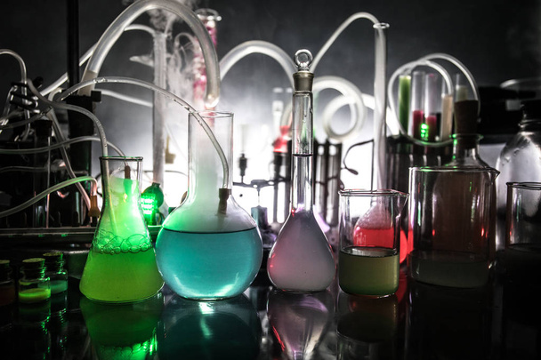 Pharmacy and chemistry theme. Test glass flask with solution in research laboratory. Science and medical background. Laboratory test tubes on dark toned background - Photo, Image