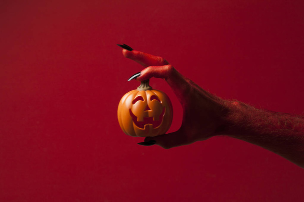 Red monster devil hand holing a pumpkin - Foto, afbeelding
