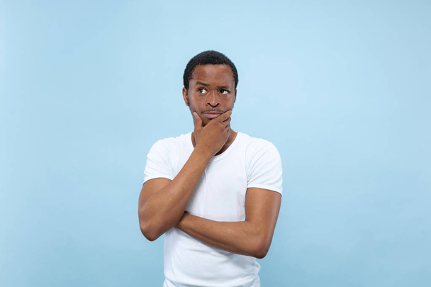 Half-length close up portrait of young man on blue background. - 写真・画像