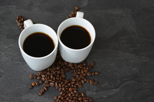 Ένα πασχαλινό λαγουδάκι φτιαγμένο από φρεσκοψημένα φασόλια καφέ που έχουν γίνει με ένα φλιτζάνι καφέ για απόλαυση φρέσκου καφέ το Πάσχα και ως Πασχαλινό δώρο με τη μορφή κόκκων καφέ - Φωτογραφία, εικόνα