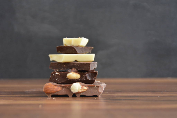 Se apilaron diferentes tipos de chocolate sobre un fondo de madera - concepto con chips de chocolate
  - Foto, imagen