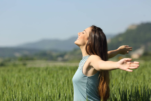 Happy woman breathing deeply fresh air in a field - Фото, изображение