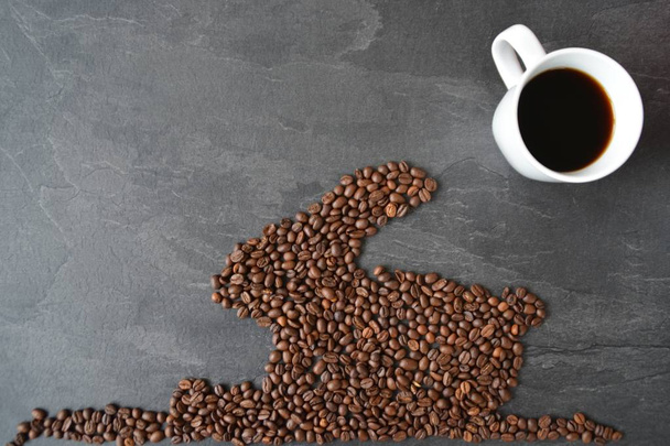 Ένα πασχαλινό λαγουδάκι φτιαγμένο από φρεσκοψημένα φασόλια καφέ που έχουν γίνει με ένα φλιτζάνι καφέ για απόλαυση φρέσκου καφέ το Πάσχα και ως Πασχαλινό δώρο με τη μορφή κόκκων καφέ  - Φωτογραφία, εικόνα