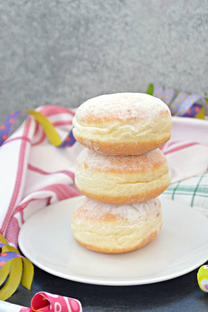Traditional donuts baked in Germany during the carnival season lie on a plate and are sprinkled with powdered sugar - a concept with so-called Krapfen at carnival time in Germany  - Photo, Image
