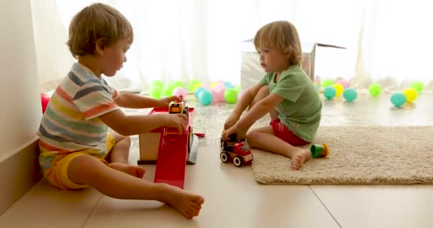 Toddlers sitting on floor and playing toy cars - Footage, Video