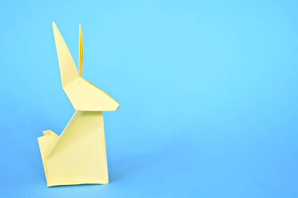 Un lapin en origami plié à partir de papier pastel repose sur une base bleue concept avec origami et place pour le texte ou d'autres éléments pour Pâques
 - Photo, image
