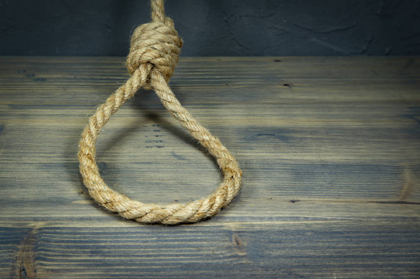 Hangman's knot on a rustic wooden table - Φωτογραφία, εικόνα