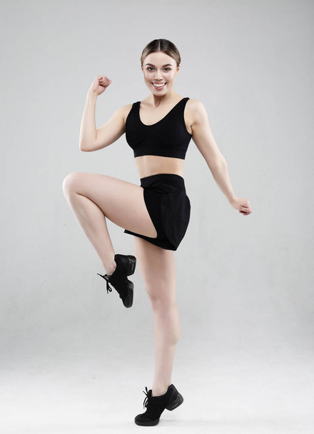 Sport, fitness and people concept: Beautiful young woman dressed in sportswear jumping up over grey background - Fotografie, Obrázek