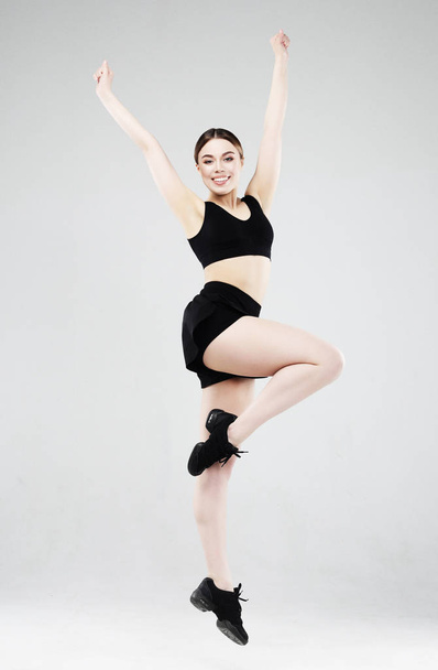 Sport, fitness and people concept: Beautiful young woman dressed in sportswear jumping up over grey background - Fotó, kép