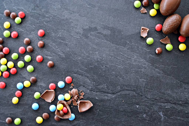 A csokoládé húsvéti nyuszi fekszik egy sötét márvány felületen színes csokoládé chips, és néhány csokitojás-koncepció édességek Húsvét a szoba a szöveg vagy más elemek  - Fotó, kép