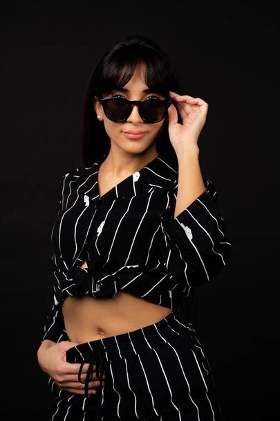 Fiatal üzleti lány egy fekete öltönyt jelentő egy fotót a fekete háttér. - Fotó, kép