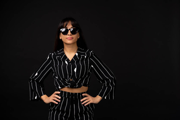 Young business girl in a black suit posing for a photo on a black background. - Photo, Image