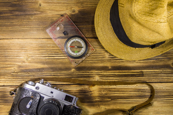 Kompas, hoed en retro fotocamera op houten achtergrond - Foto, afbeelding