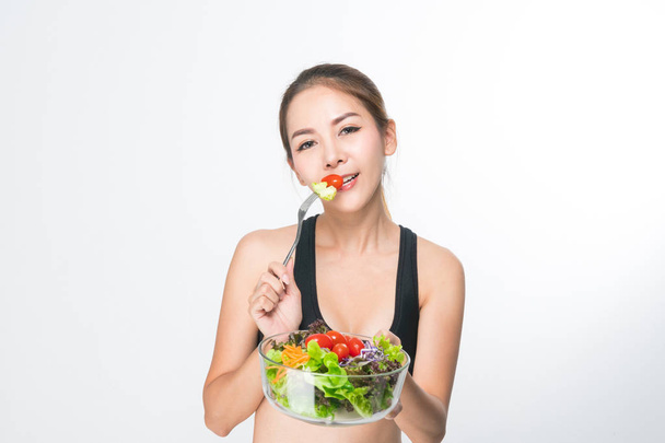 Girl in a fitness suite holds a salad bowl. - Photo, Image