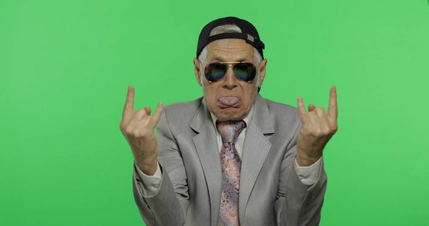 Divertido hombre de negocios senior en gafas de sol muestran signo de los cuernos con sus manos
 - Foto, Imagen