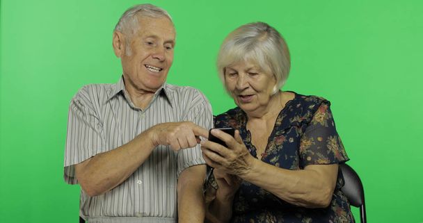 Starší muž a žena seděli pohromadě a pracovali na telefonu. Klíč Chroma - Fotografie, Obrázek