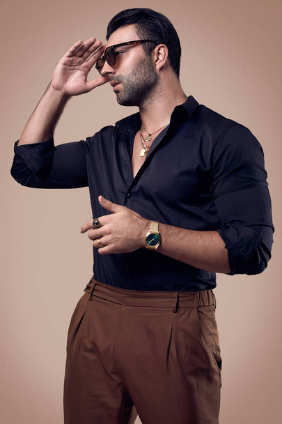Beautiful brutal tanned hipster man in a black shirt and glasses - Photo, image