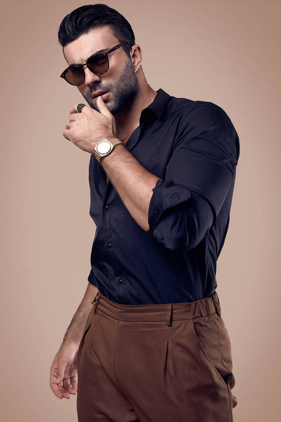 Beautiful brutal tanned hipster man in a black shirt and glasses - Foto, Bild
