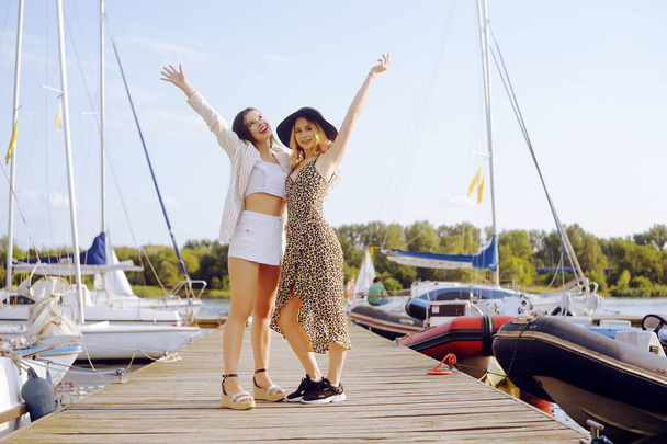 Two girls on the background of yachts, sailing boats are smiling - Fotoğraf, Görsel