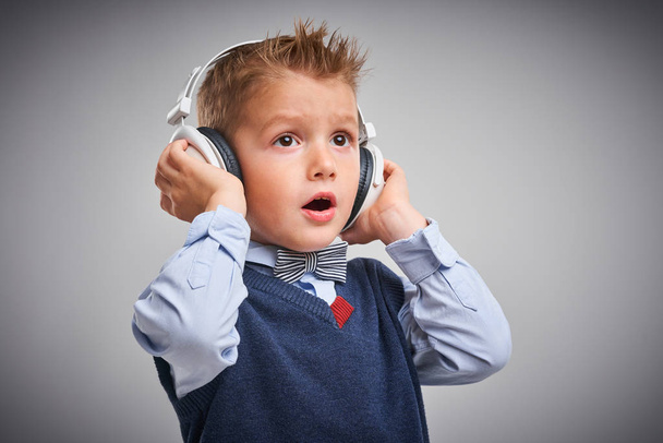 Portrait d'un garçon de 4 ans posant sur blanc avec écouteurs
 - Photo, image