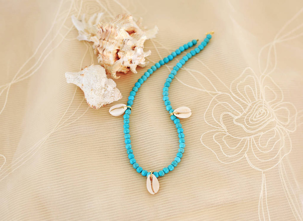 colar com pedras semi-preciosas turquesa e conchas - anúncio de jóias de verão - fundo de tule marrom
 - Foto, Imagem