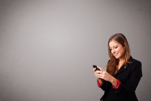 young lady standing and holding a phone with copy space - Фото, изображение