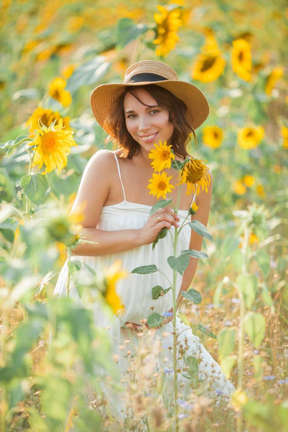 Beautiful young pregnant woman in the sunflower field. Portrait of a young pregnant woman in the sun. Summer. - Φωτογραφία, εικόνα