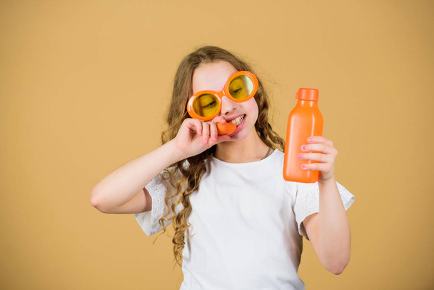 Fashion kid sunglasses drink refreshing vitamin juice. Health care. Summer vitamin diet. Happy childhood. Natural vitamin source. Girl eat carrot vegetable and drink carrot juice. Vitamin nutrition - 写真・画像