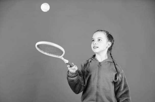 Girl adorable child play tennis. Practicing tennis skills and having fun. Athlete kid tennis racket on blue background. Active leisure and hobby. Tennis sport and entertainment. Focused on ball - Foto, Bild
