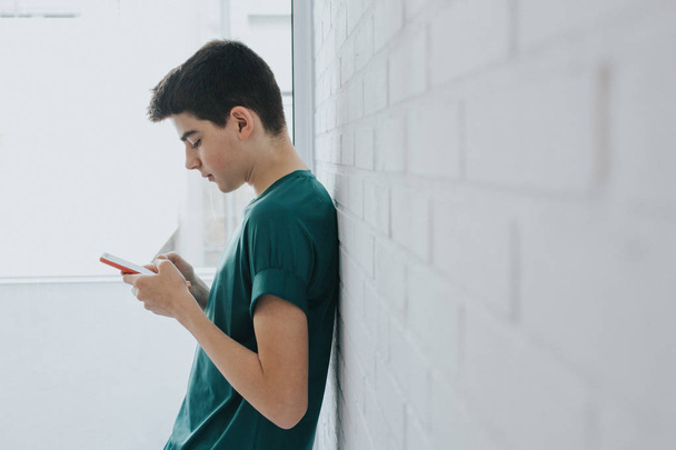 νέος ή Έφηβος με το κινητό τηλέφωνο στον τοίχο - Φωτογραφία, εικόνα